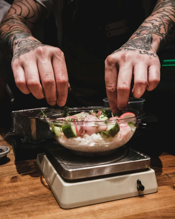 tattooed man prepares to dip his food in the bowl