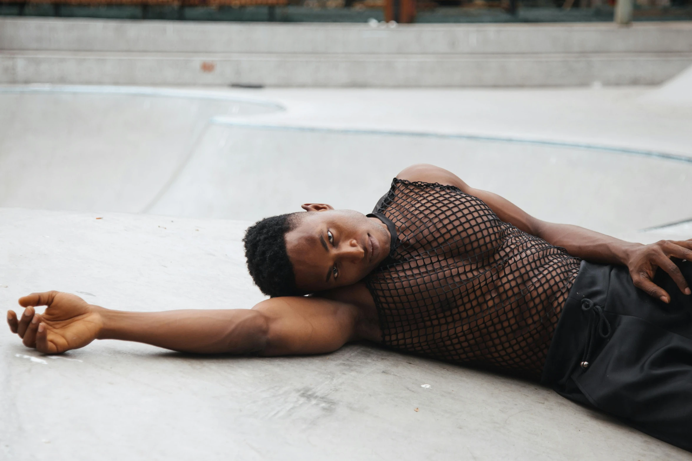 a man lying on a concrete slab near a pool