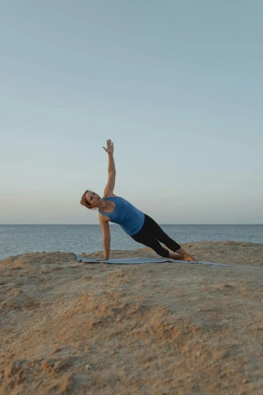 a woman practicing yoga on the beach