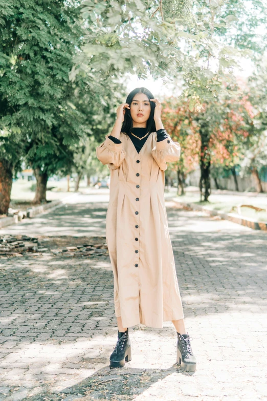 a  wearing a coat and a hat while walking through the park