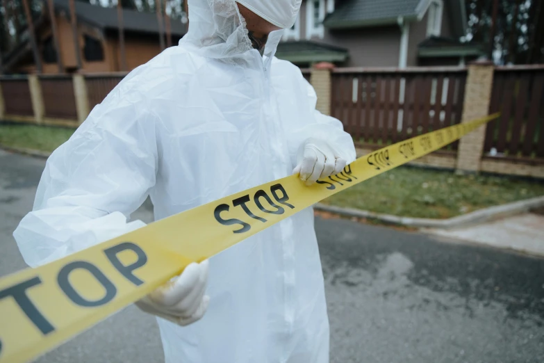 a man in a protective suit holding two yellow caution tapes