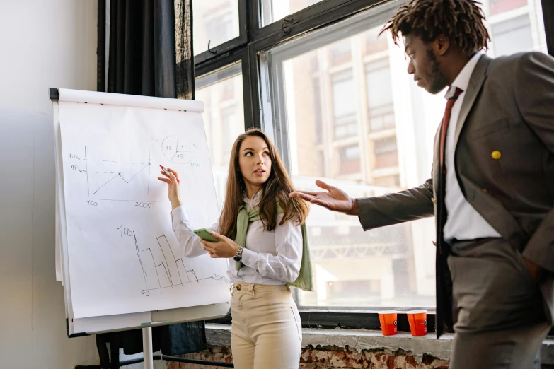 there is a woman standing in front of a whiteboard talking to a man