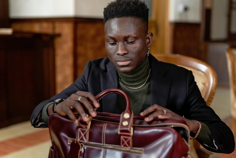 a young man holds a leather briefcase in his hands