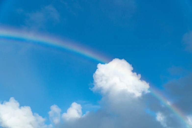 a rainbow is seen in a cloud filled sky