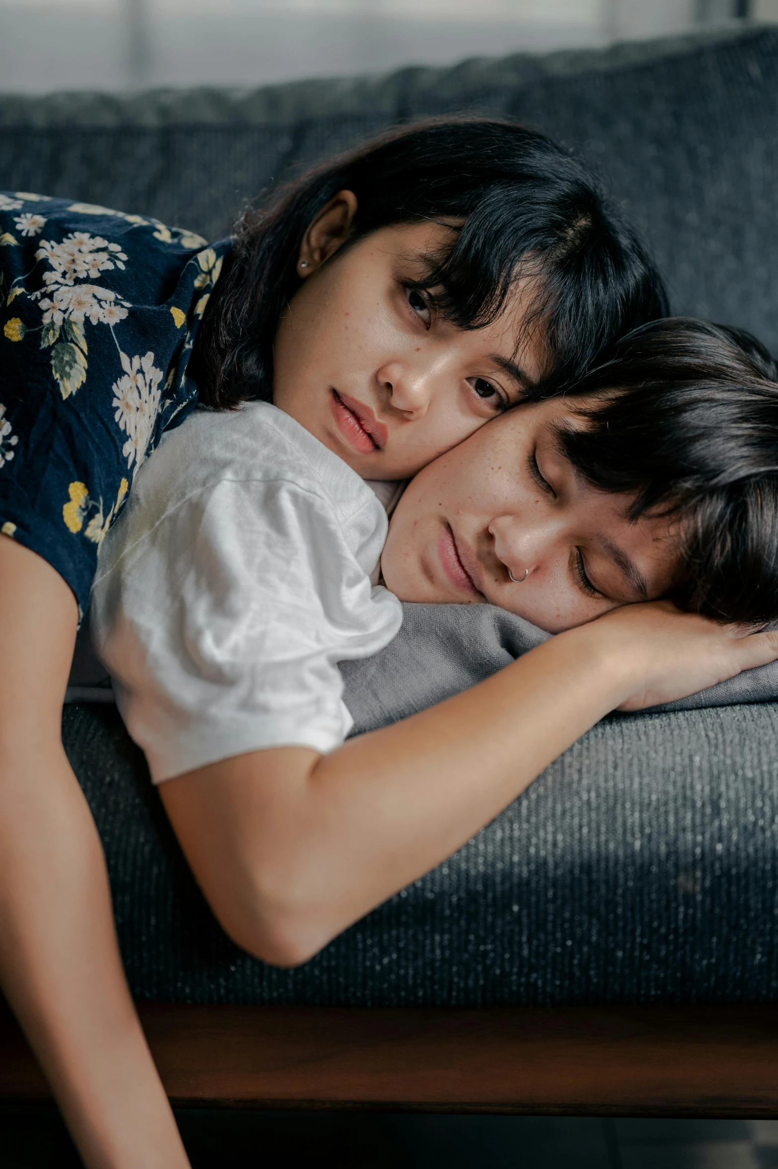 two girls that are laying on a couch with pillows