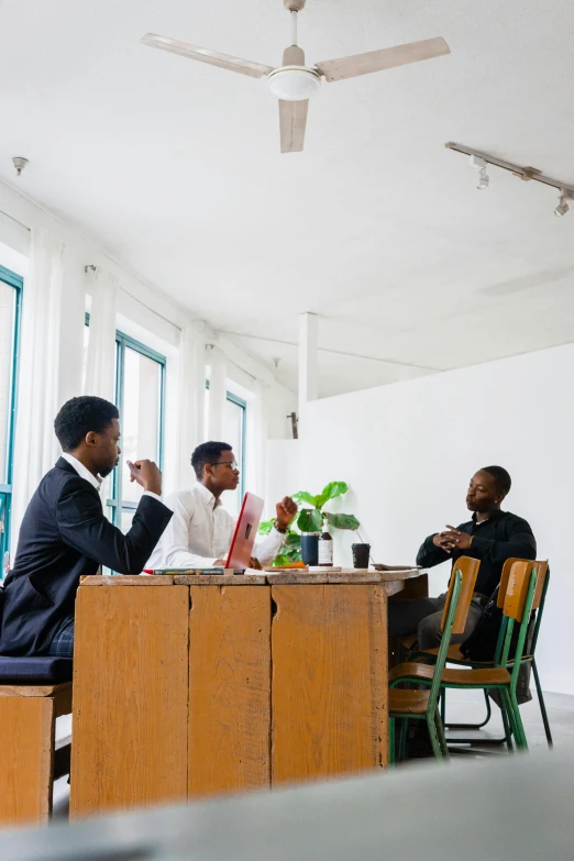 people at a table having a meeting in a room with large windows