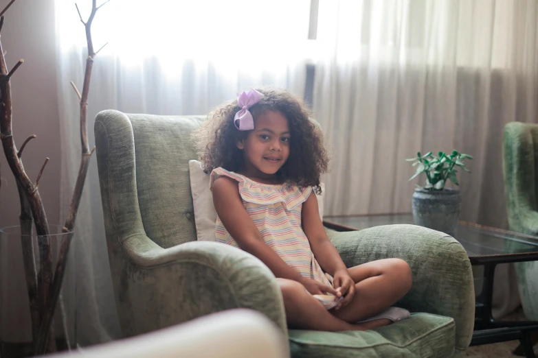 the little girl smiles while sitting in a chair