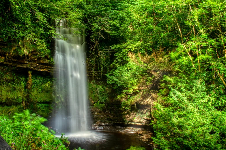 a large waterfall surrounded by trees in the woods