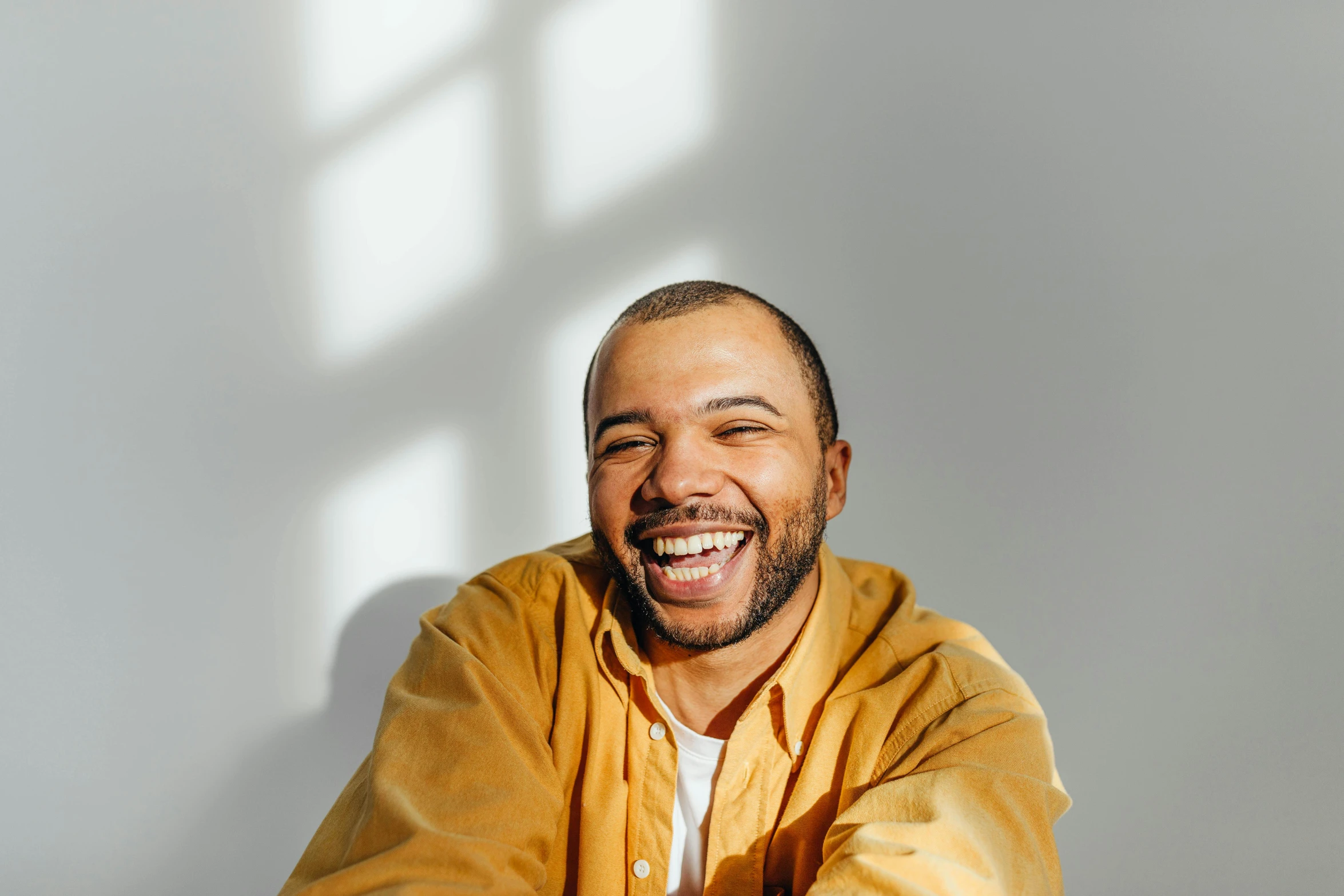 a man wearing a jacket standing in front of a white wall