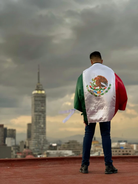 a person holding a mexican flag and looking at the city skyline