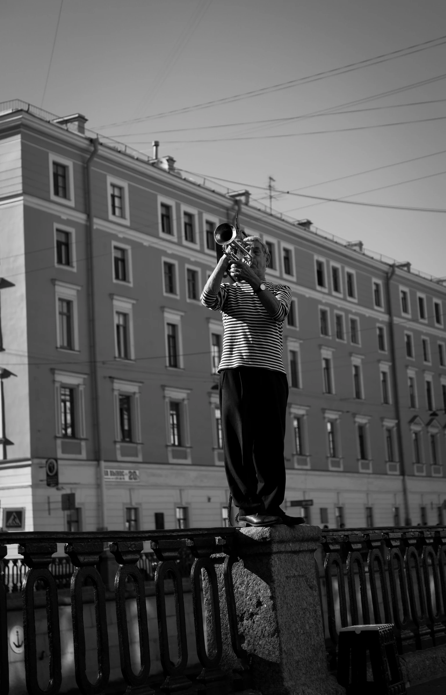 a man standing on top of a stone fence next to tall buildings