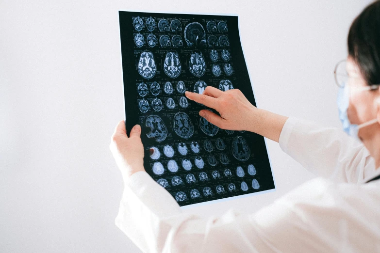 a woman in glasses and white shirt holding up an x - ray