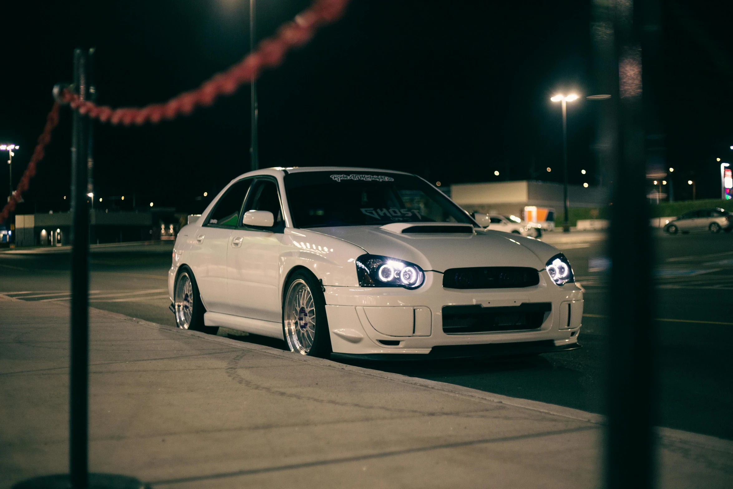 a white car sitting in a parking lot at night