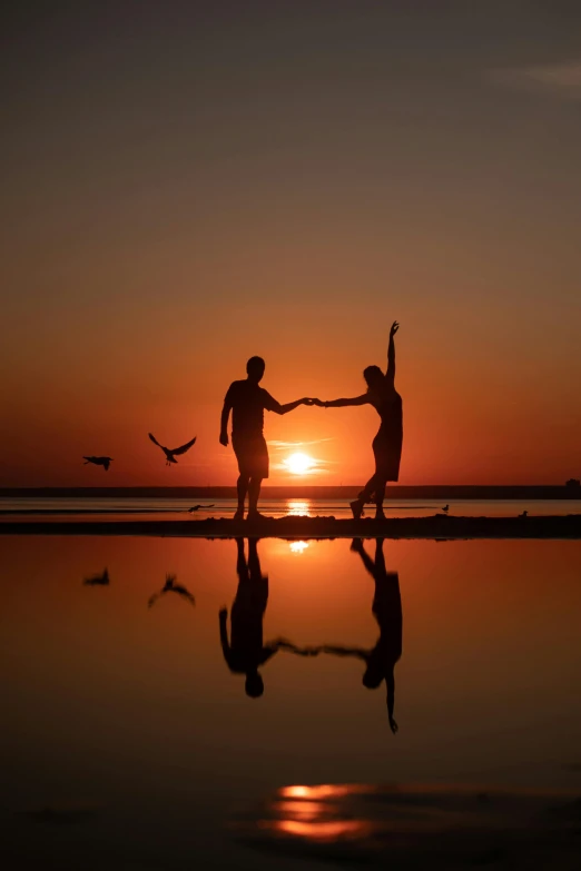 two people in silhouette against an orange and blue sky