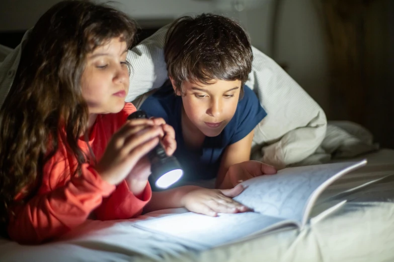 two s are laying on their bed playing with the light