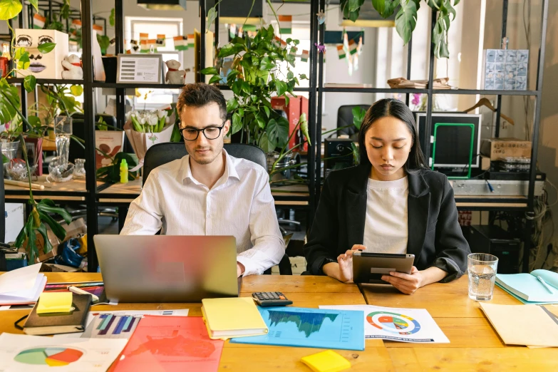 a woman and man sitting next to each other in front of a laptop