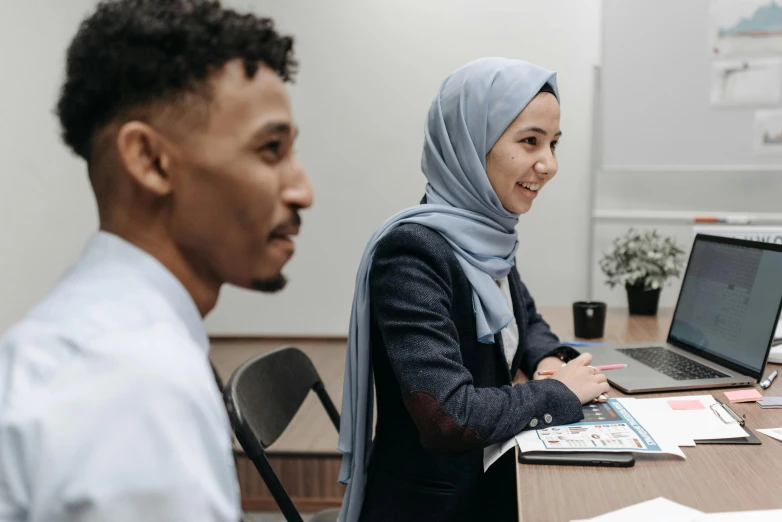 two people sitting at a table with laptops