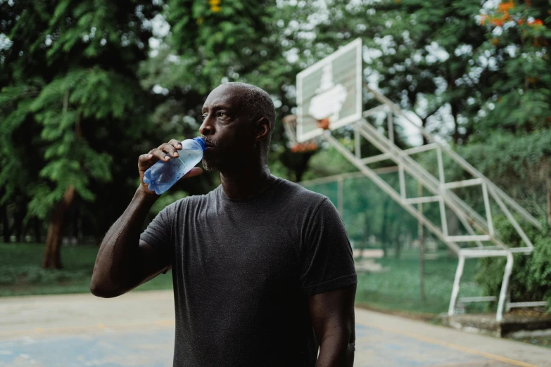 a man is drinking from a bottle in the court