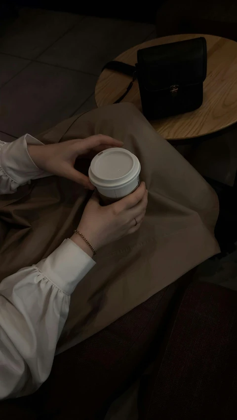 a person holding onto a white cup in their hands