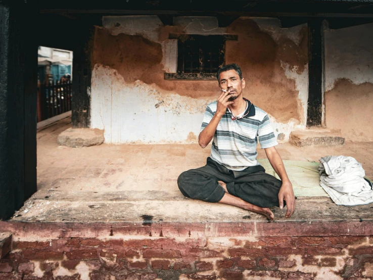 a man is sitting on the doorstep talking on his cell phone