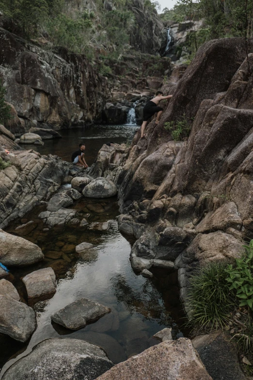 the person is laying on rocks next to the stream