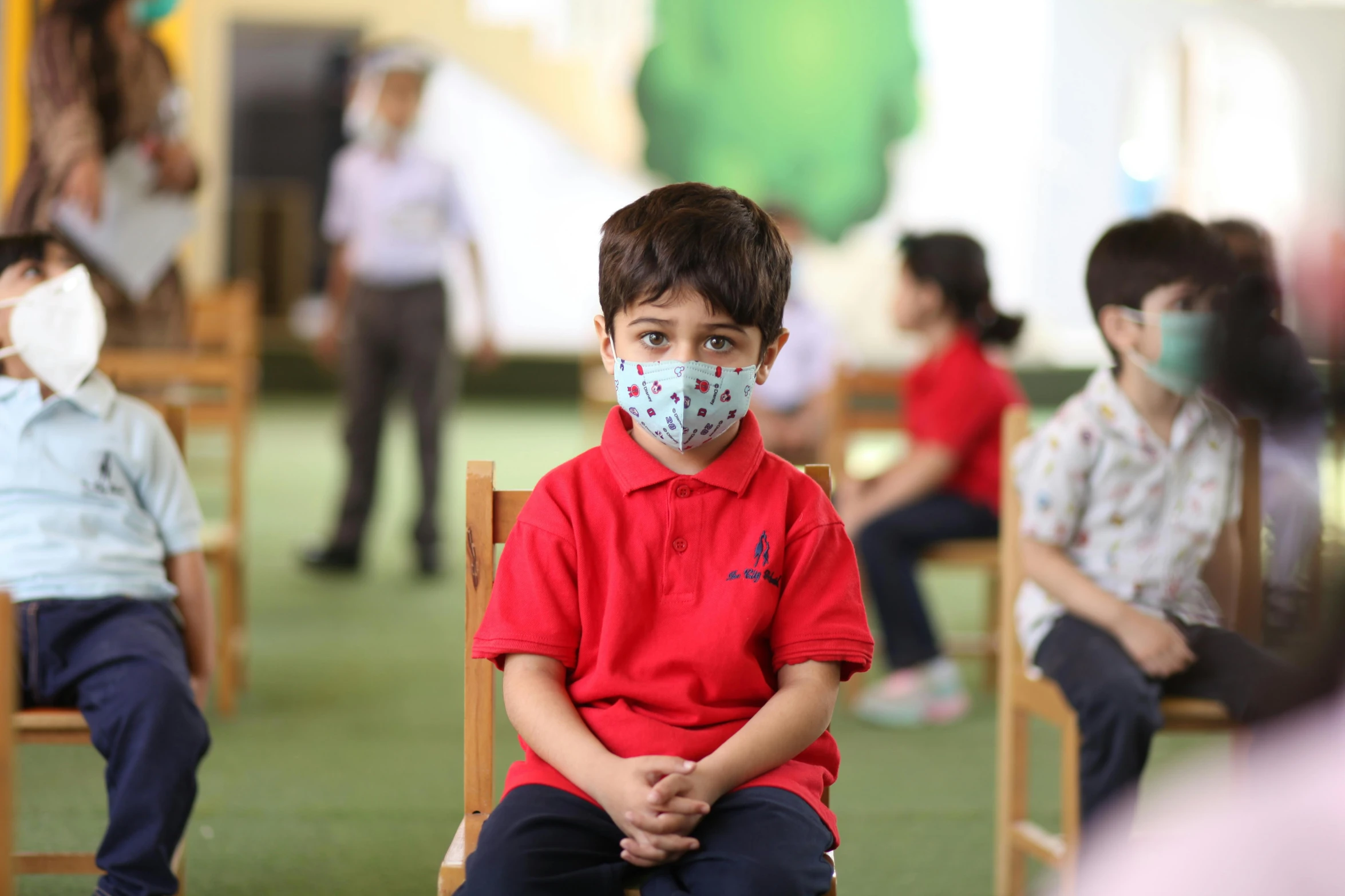 a  wearing a face mask sitting in front of other s