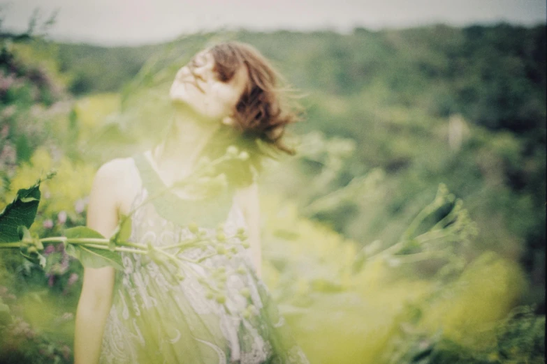 the woman is standing among the grass and flowers