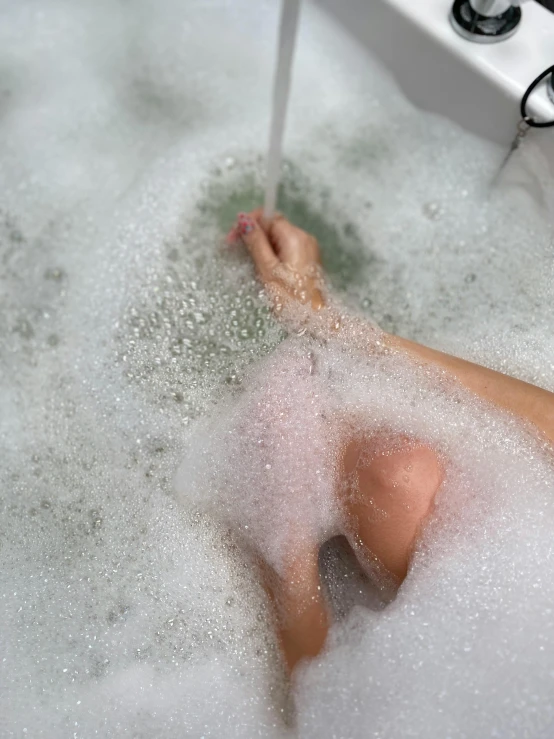 woman sitting in a bubble bath in the shower
