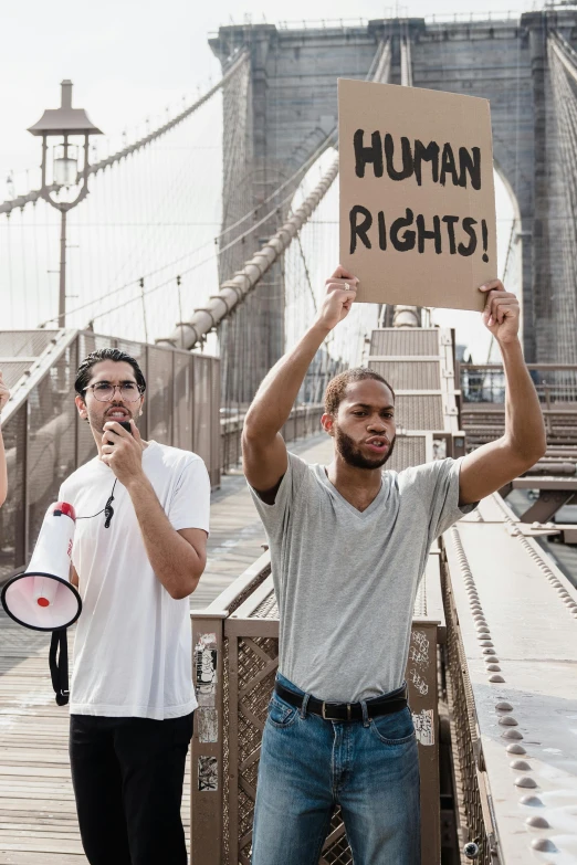 people standing in front of the brooklyn bridge holding up signs