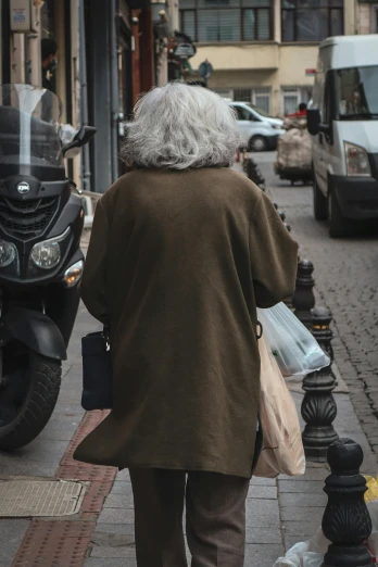 a man walking down a city street wearing a brown coat