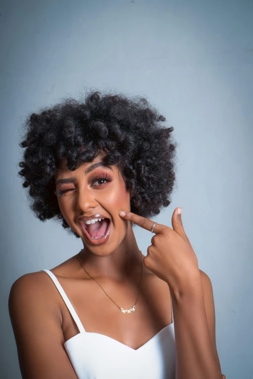 a woman poses in front of the camera holding her finger to her lip