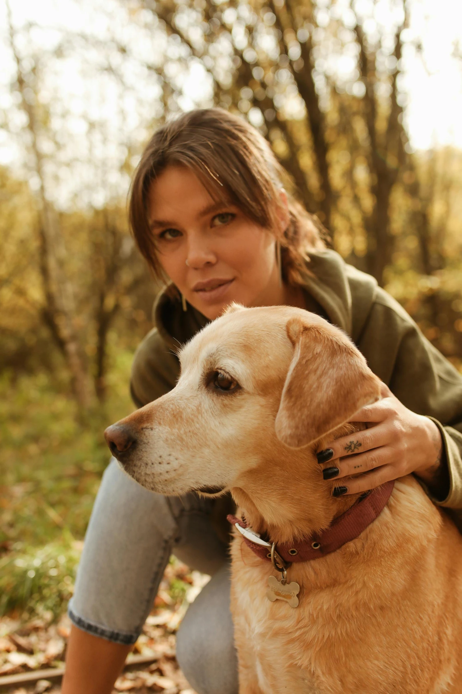 woman sitting in autumn leafy ground with her dog