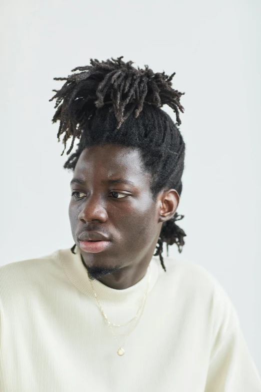 a person with dreadlocks is standing in front of a white backdrop