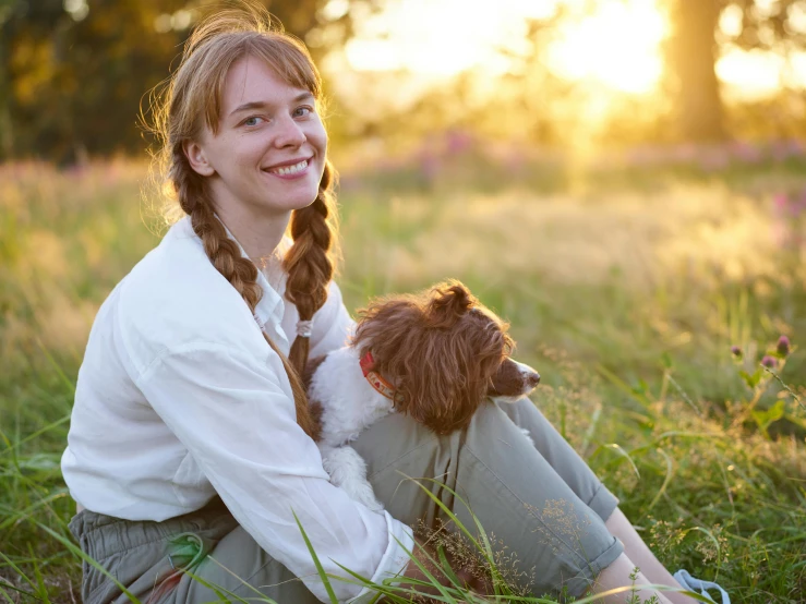 a girl sitting on the grass holding a stuffed animal