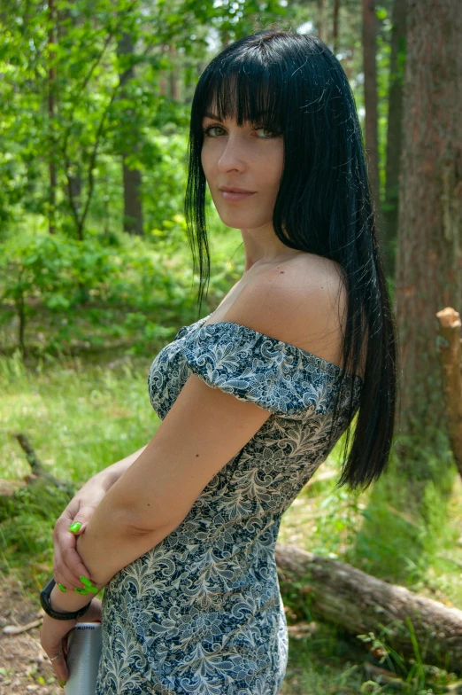 woman standing in forest posing with sword and wearing green dress