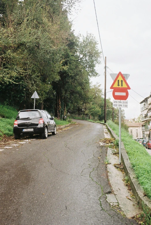 car parked in front of a traffic sign on the side of a road