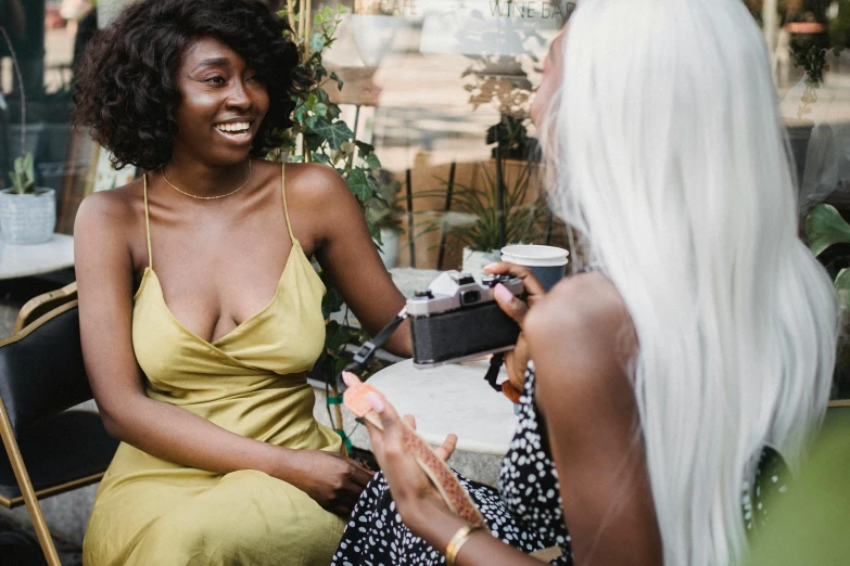 two women talking while sitting in chairs in a courtyard