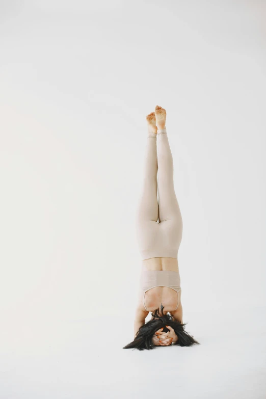 an individual doing a handstand against a white background