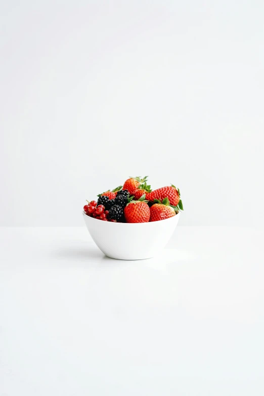 a bowl of berries in white bowls with one fruit on top