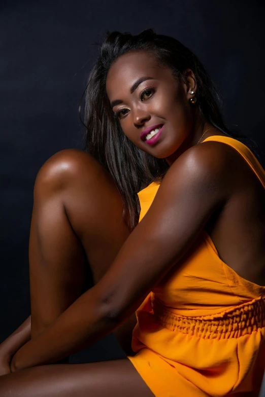 a beautiful young woman sitting down wearing yellow clothing