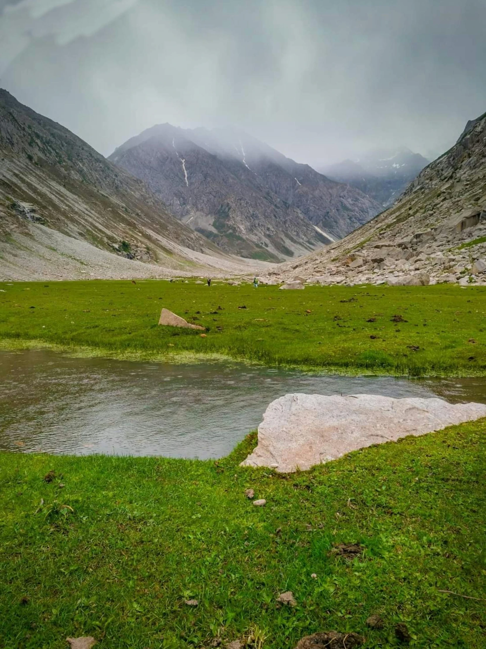 this green valley is next to a small lake