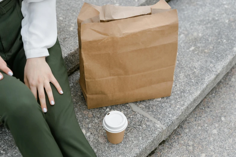 a close up of a person sitting on stairs with a cup of coffee