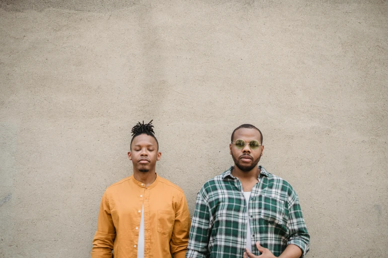 two young men standing in front of a concrete wall