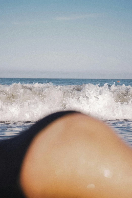 a person laying on a surfboard in front of a crashing wave