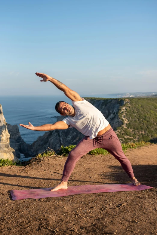 a man is standing on a yoga mat outdoors