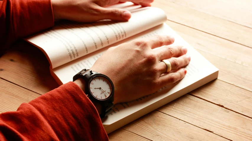 a person reading a book with his hands on a wrist