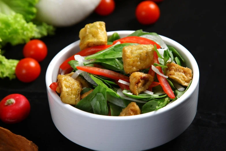 a bowl of tofu sitting next to tomatoes and lettuce