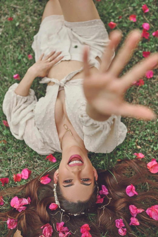 a woman lays down in the grass with her hands up