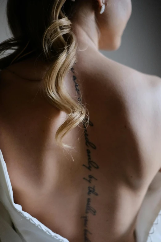 a woman with a back tattoo holding a wine glass