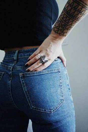 a woman in tight jeans has a tattoo on her arm